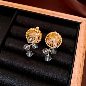 Macro detail of vintage gold hollow earrings with transparent crystal fringe tassels