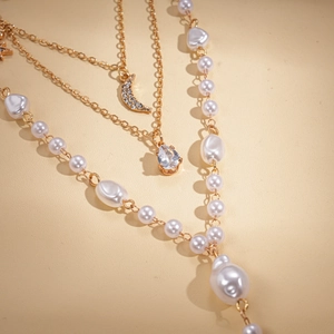 Layered gold necklace with baroque pearls, crescent moon pendant and sparkling crystals
