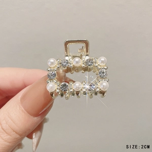 Detailed macro view of 2cm gold-toned mini hair claw clip with pearls and crystals
