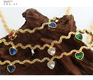 Close-up of heart-shaped zircon pendants on gold twisted chains over natural wood