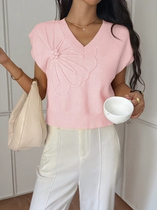 Detail of pink knitted V-neck vest featuring a large 3D floral applique on the chest