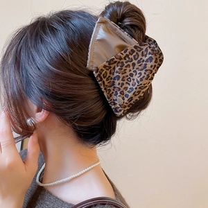 Detail view of large leopard print hair claw clip on model with elegant styling