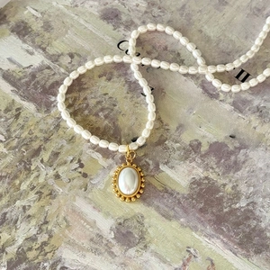 Vintage pearl necklace with oval gold pendant on artistic oil painting background
