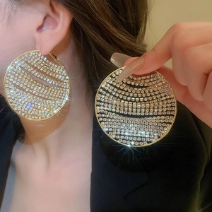 Close-up of oversized gold geometric hoop earrings with multi-row pavé crystals