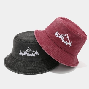 Détail de la broderie forêt de montagne sur des bobs en coton délavé gris et bordeaux