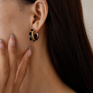 Détail d'une boucle d'oreille créole dorée entrelacée de velours noir élégant