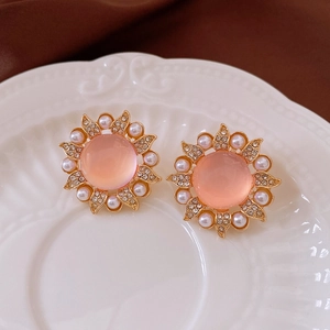 Détail de boucles d'oreilles tournesol avec opale rose, perles et cristaux sur plateau