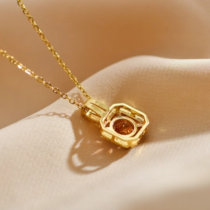 Macro shot of gold square pendant back with hollow structure and orange gemstone
