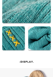 Macro detail of dark teal knit fabric with thick texture and yellow cross-stitch embroidery