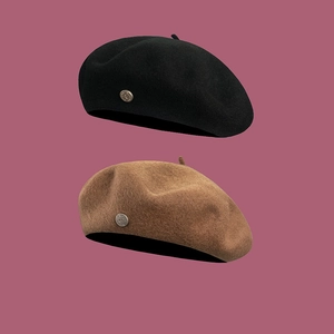 Classic wool beret hats in black and brown with metal badge decor in a portrait view