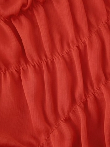 Detailed close-up of vibrant red mesh pleated fabric with delicate vertical textures
