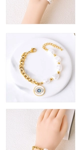 Close-up of golden chain bracelet with Baroque pearl and blue Evil Eye charm detail