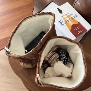 Detail of embroidered faux suede makeup bag showing spacious interior and floral texture