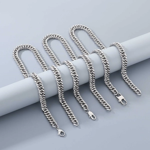 Close-up of polished stainless steel curb link necklaces on cylindrical props