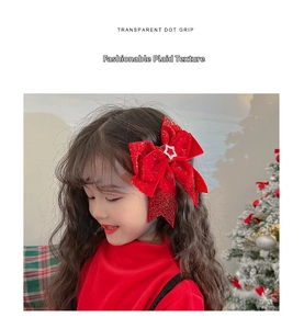 Detail of red bow hair clip with silver star charm worn by a child for festive holiday