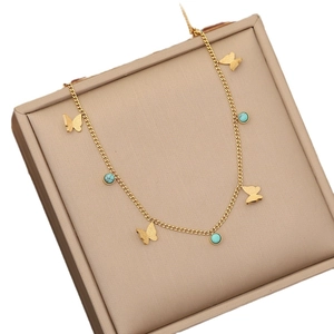 Golden stainless steel necklace with butterfly pendants and turquoise beads on beige box