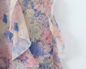 Detailed close-up of floral chiffon fabric with ruffled edges and white overlock stitching