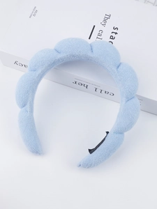Light blue puffy sponge headband with wave design resting on white books