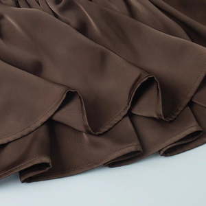 Detailed close-up of dark brown satin fabric showing ruffled hem and smooth silk texture