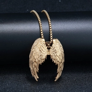 Détail du pendentif ailes d'ange dorées suspendu sur un support texturé noir