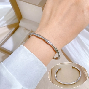 Detailed view of a silver bamboo joint open bangle on a model wrist and jewelry box