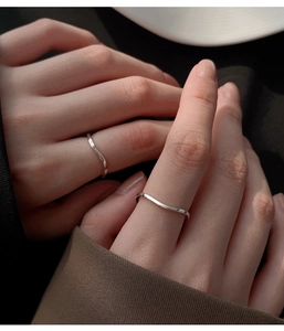 Close-up of minimalist S925 sterling silver wave rings on fingers with smooth metal finish