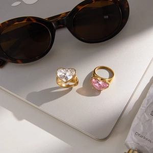 Luxe stainless steel heart rings with pink and clear crystals on a laptop surface