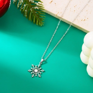 Macro shot of silver stainless steel snowflake pendant on green festive background