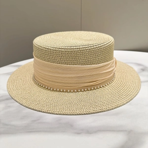 Close-up of fine straw boater hat featuring champagne ribbon and pearl decoration
