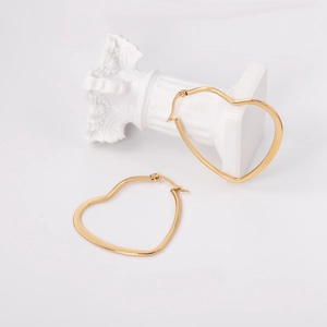 Minimalist golden stainless steel heart hoop earrings on a decorative white pillar base