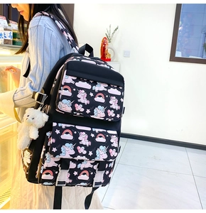Detail of black nylon unicorn school bag featuring pink rainbows and plush bear charm