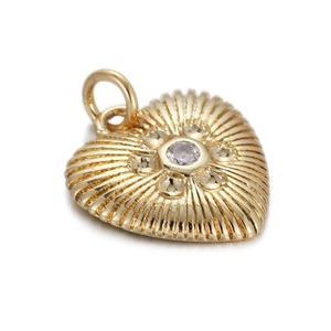 Detail of a gold heart pendant featuring radial texture and a sparkling center zircon