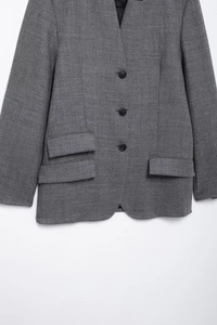 Detail of single-breasted buttons and flap pocket on a grey retro commuter blazer