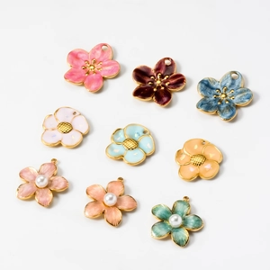 Flat lay of nine colorful enamel flower pendants with pearls for jewelry making