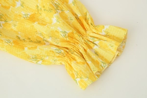 Close-up of yellow floral chiffon sleeve with elastic ruffled cuff and crinkle texture