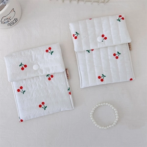 Detail of quilted cherry print cotton wash bags with snap button and brand label