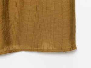 Detail shot of tan fabric showing vertical crinkle texture and fine stitching on the hemline