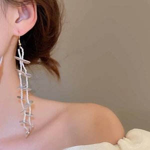 Detail of silver long drop earrings with white beads on model for beach vacation
