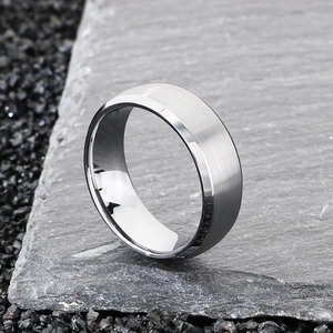 Close-up of brushed tungsten steel ring with polished beveled edges on natural stone