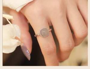 Close-up of silver-tone square white jade ring with pavé diamond bezel on model hand