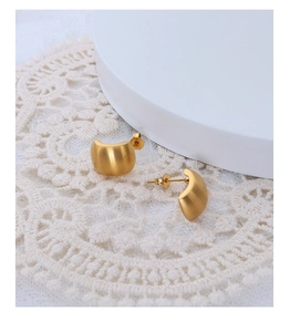 Detail of matte 18K gold plated C-shaped hoop earrings on elegant white lace background