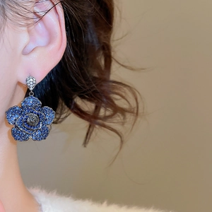 Detailed close-up of blue zircon floral drop earrings with a vintage petal design