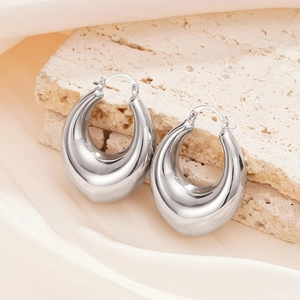 Macro shot of silver chunky hoop earrings with mirror finish on stone and silk props