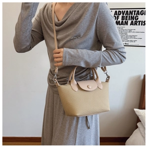 Detail of woven texture dumpling bag with leather flap and adjustable shoulder strap