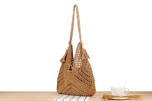 Detail of woven triangle bag in camel with hollow pattern, fringe, and a matching strap