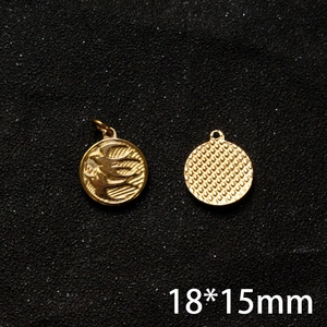 Macro detail of 18x15mm golden swallow charm showing front bird pattern and textured back