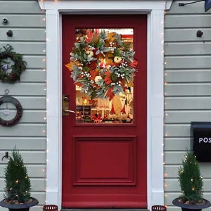 Autumn wreath with white pumpkins and maple leaves hanging on a red rustic door
