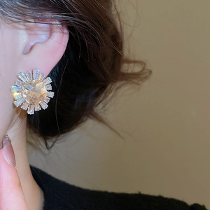 Close-up of a silver sunflower crystal earring featuring sparkling zircon on a model