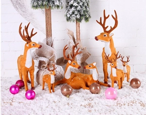 Detailed view of various reindeer figurines with flocking texture in snowy forest scenery