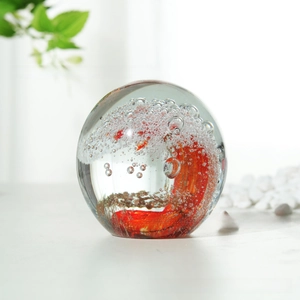Macro detail of artisan glass paperweight with swirling red waves and golden glitter texture